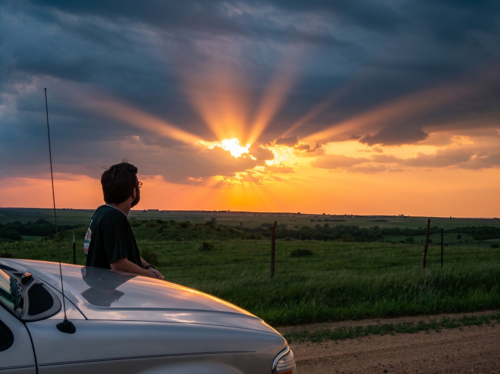Dr. Mac watching a dramatic sunset over the Great Plains beside a vehicle